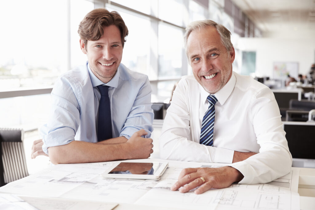 Two male architects working together, looking to camera